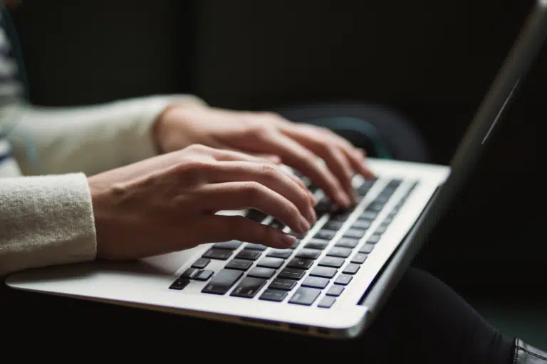 A shot of a woman's hands typing on an Apple MacBook