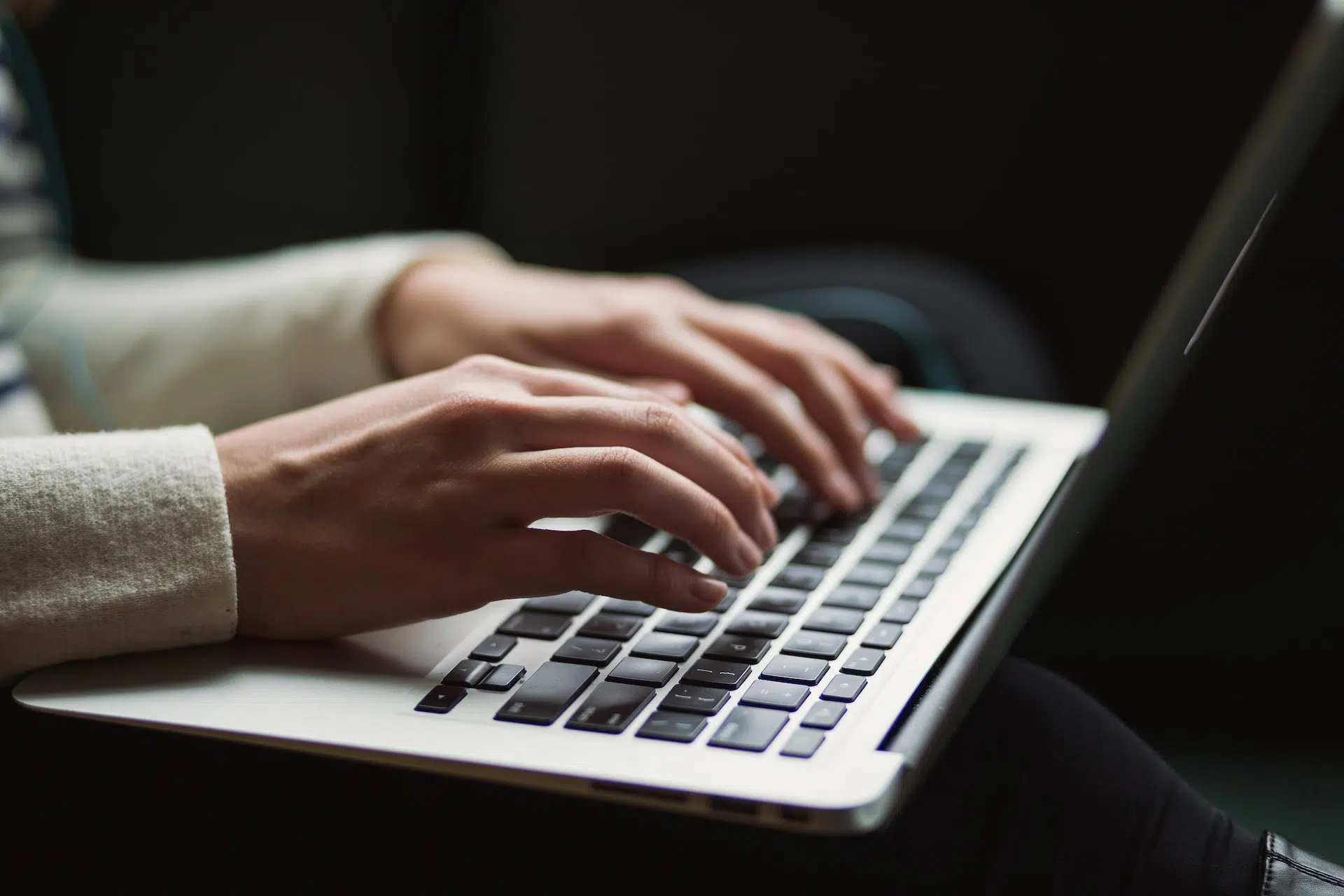 A shot of a woman's hands typing on an Apple MacBook