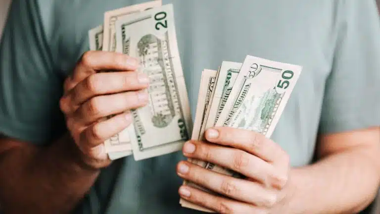 A man holding dollar bills to illustrate the question "how much does it cost to start a blog?"