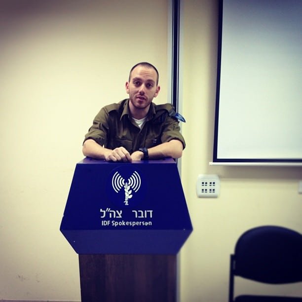 A photo of david ruhm in military uniform speaking behind a podium of the idf spokesperson's unit